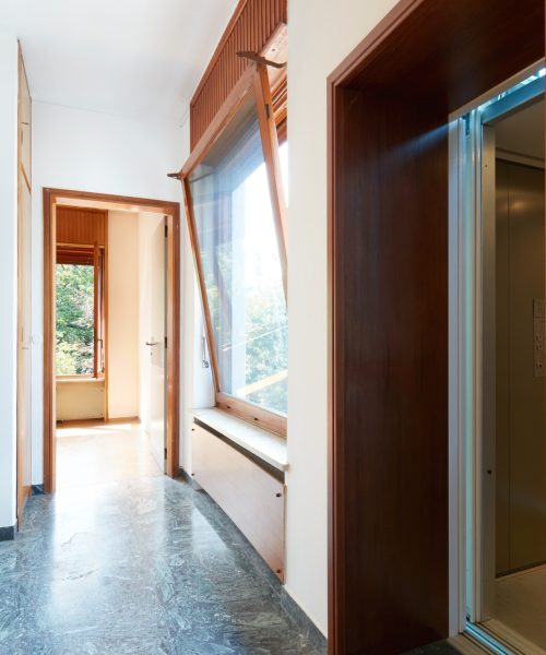 Corridor with wooden wardrobe, window and elevator door
